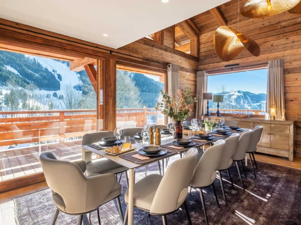 Salle à manger du Zaru Lodge avec baies vitrées et vue sur la montagne. 