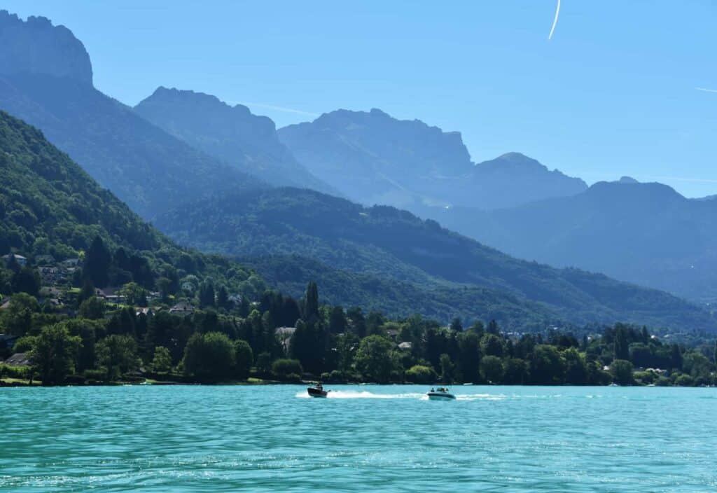 Two speed boats on Lake Annecy and hazy mountains in the backdrop