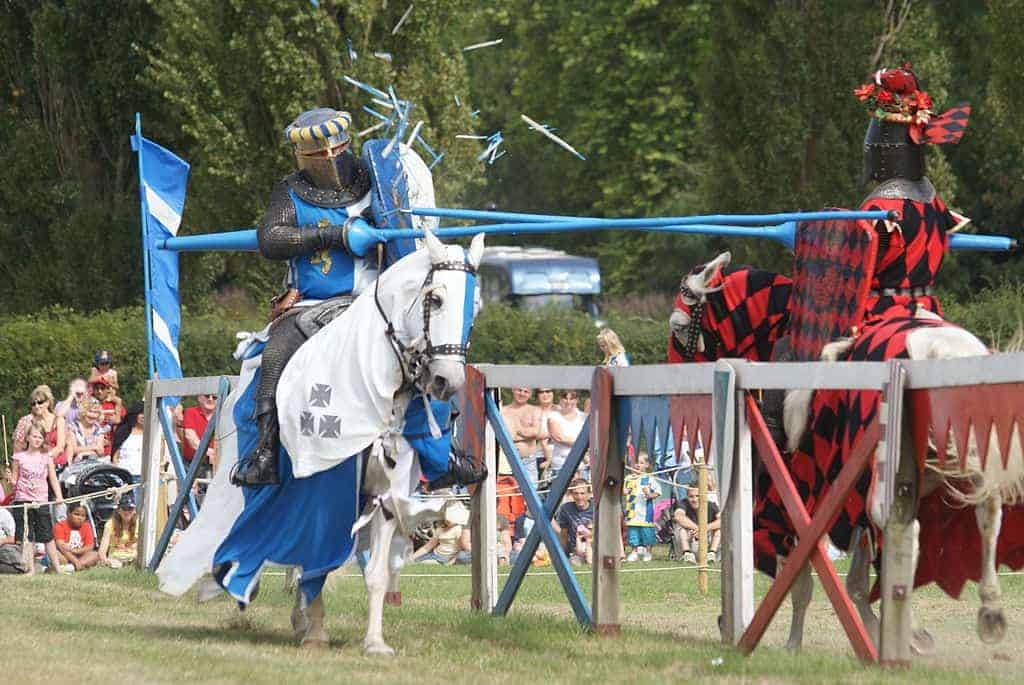 Joutes entre deux chevaliers en armure complète à cheval observés par des familles au festival médiéval dans les Alpes