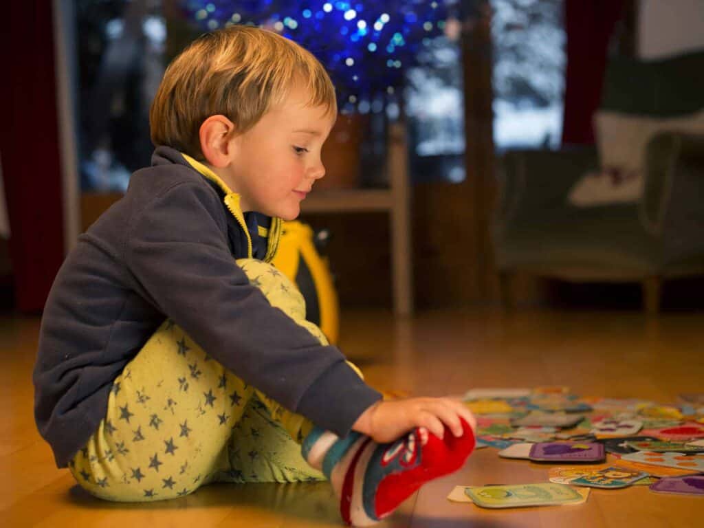 Petit garçon en pyjama en train de jouer aux cartes dans une propriété adaptée aux enfants à la montagne.