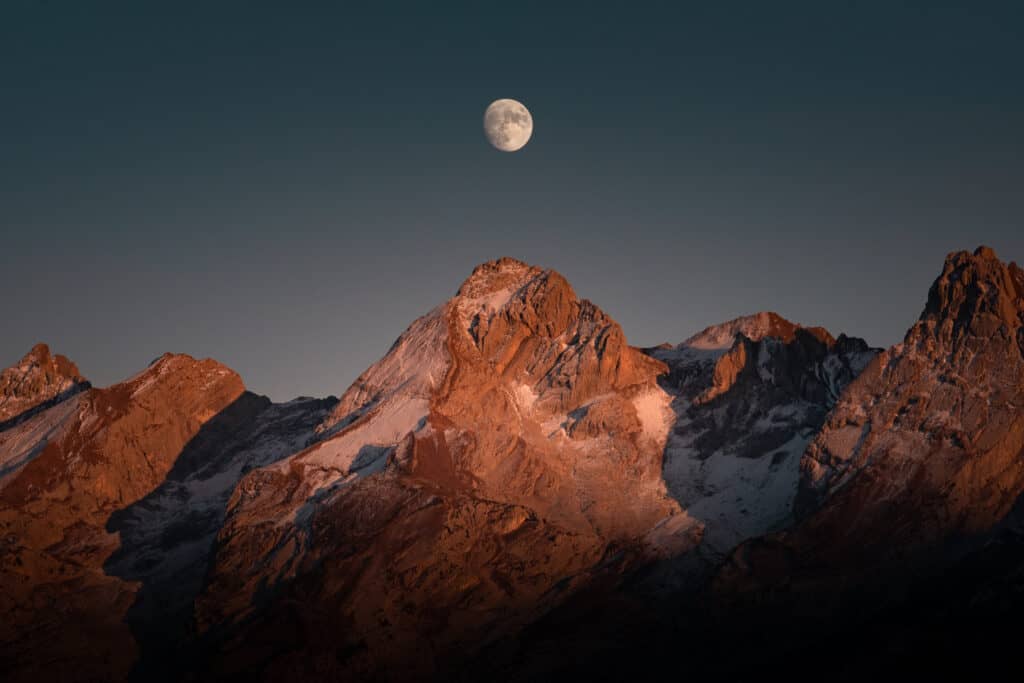 La lune d'automne donne une teinte orangée aux montagnes.