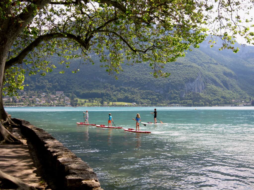 Four paddleboarders explore the shores of Lake Annecy