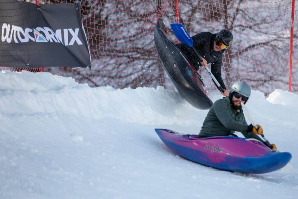 Two men use kayaks to participate in a race on the snow