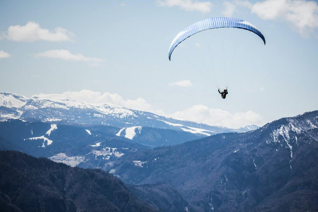 A paraglider soars over the mountain tops