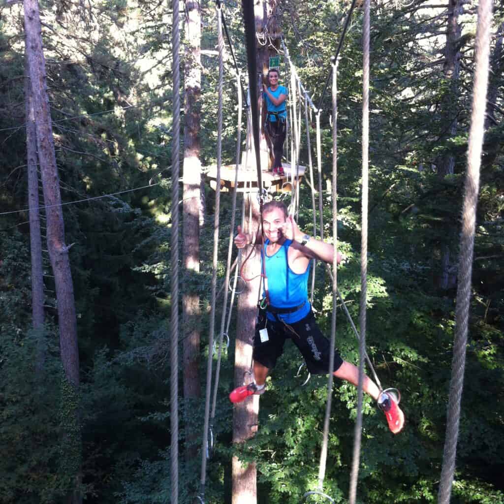 Deux personnes en plein parcours d'accrobranche à Acro'Aventure Talloires-Montmin. 