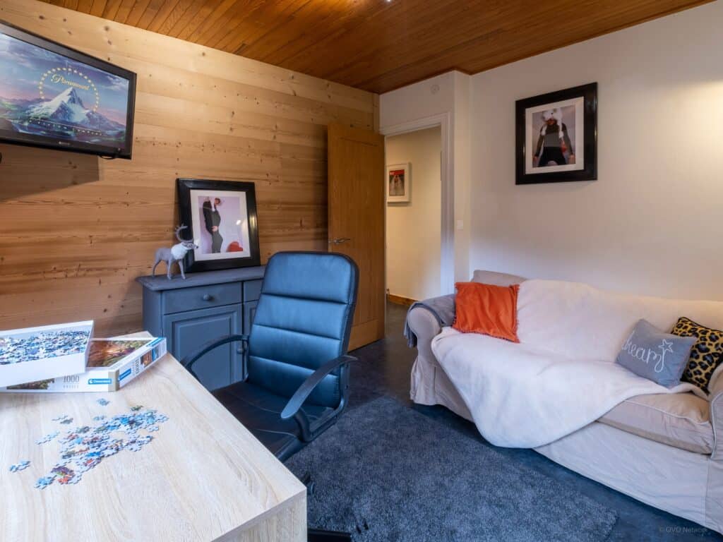 Le salon TV du chalet Bolay, avec une chaise ergonomique, une table de travail et un canapé confortable.