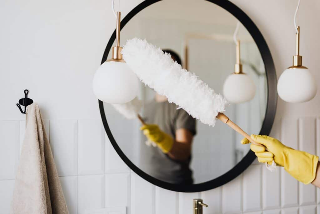 Personne en train de nettoyer un miroir dans une salle de bain. 