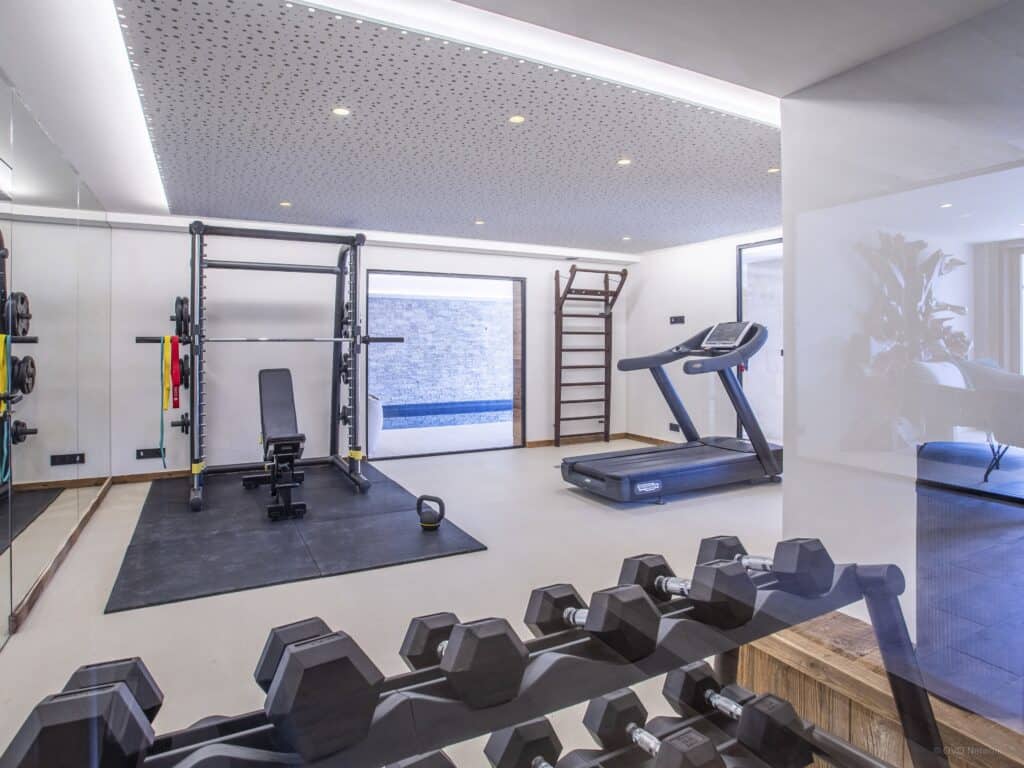 Salle de sport de la Ferme de Mila, avec poids et machine pour courir.