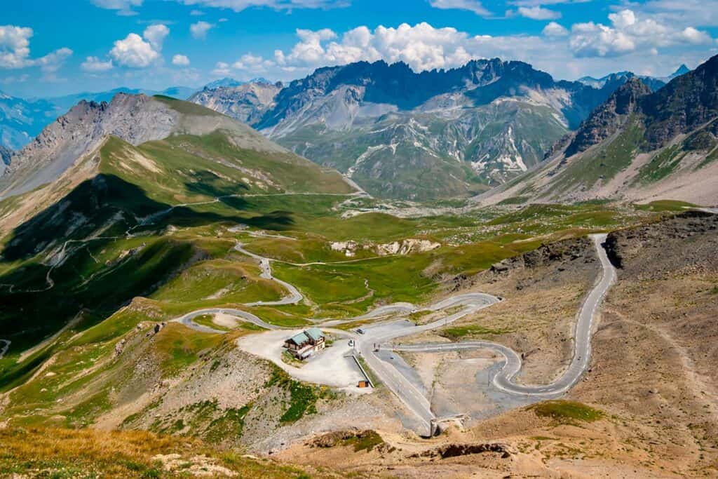 A winding road, a chalet and mountains as far as the eye can see