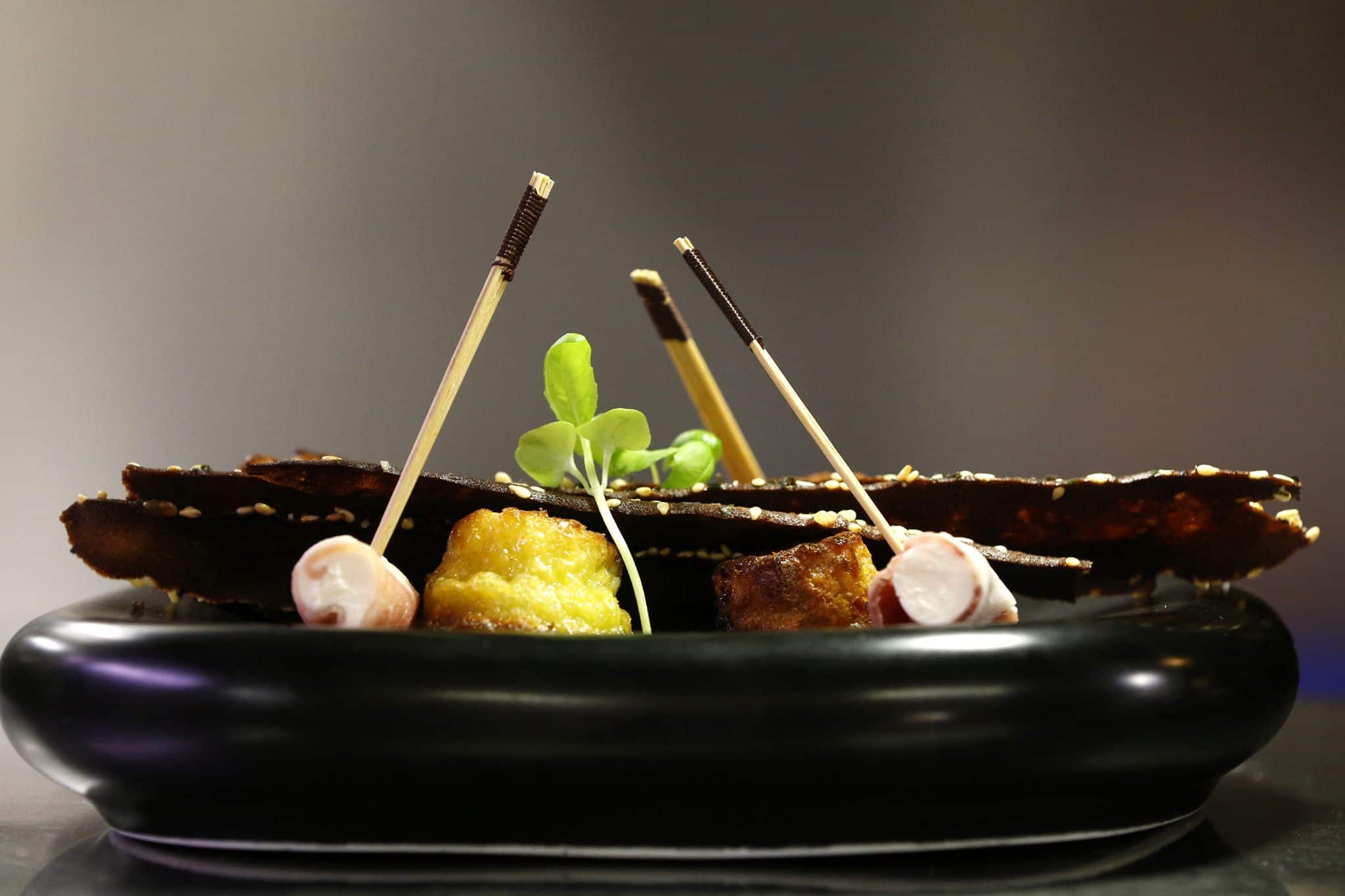 Plat cuisiné et servi dans une assiette noire.