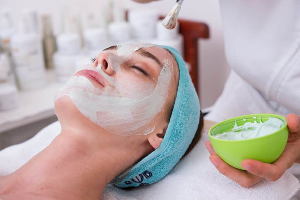 Un masque facial est appliqué sur le visage d'une femme dans un spa.