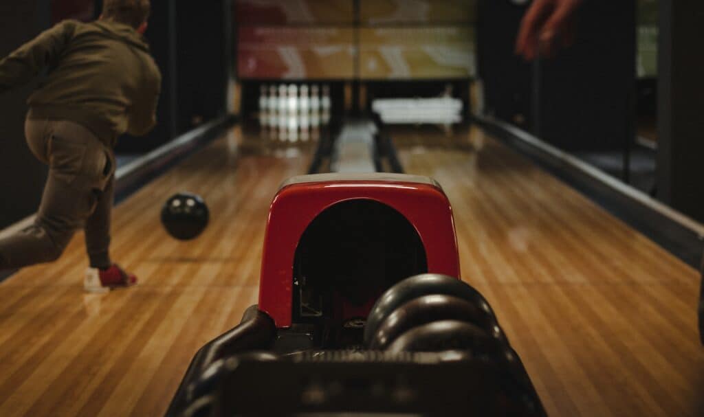 A man throws a bowling ball down a bowling lane