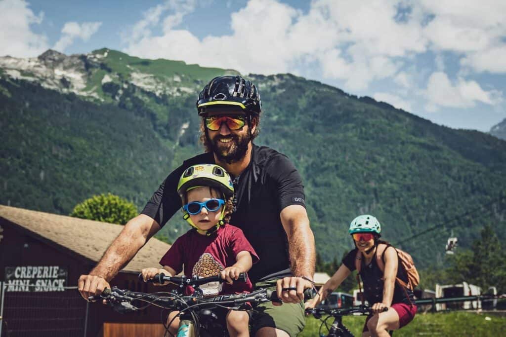 Famille heureuse à vélo avec les montagnes en arrière-plan.