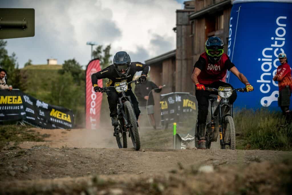 Deux cyclistes enduro s'affrontent lors du Megavalanche, l'un des évènements à ne pas perdre cet été dans les Alpes.