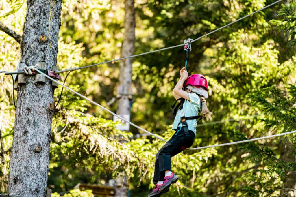 A little girl enjoying a tree-climbing activity thanks to the Multipass