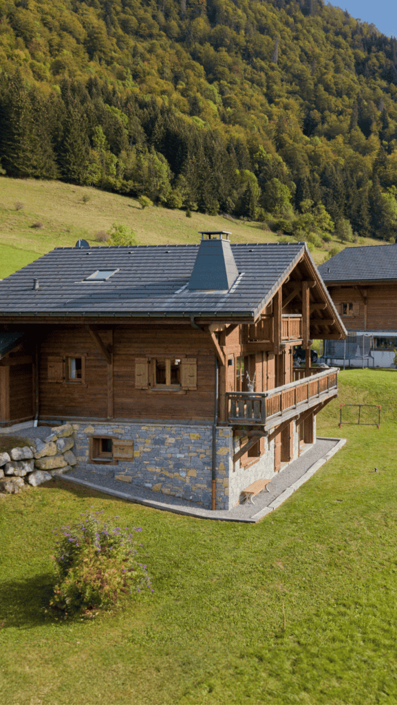 Vue extérieurs d'un chalet en pierre et en bois entouré de verdure