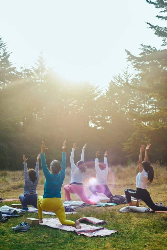 Un groupe de femmes faisant du yoga à l'orée d'une forêt alpine.