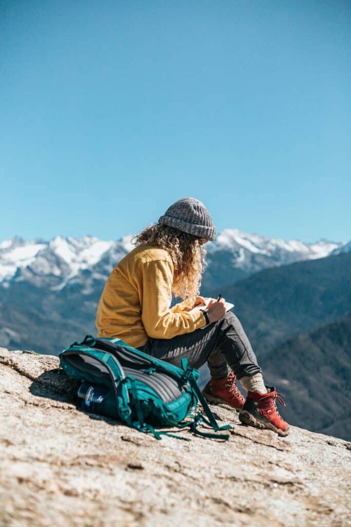 A woman writes in a journal in the mountains