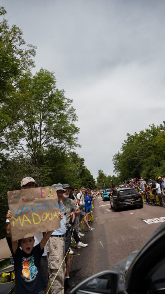 The crowd expecting the Tour de France, with a young boy holding a sign.