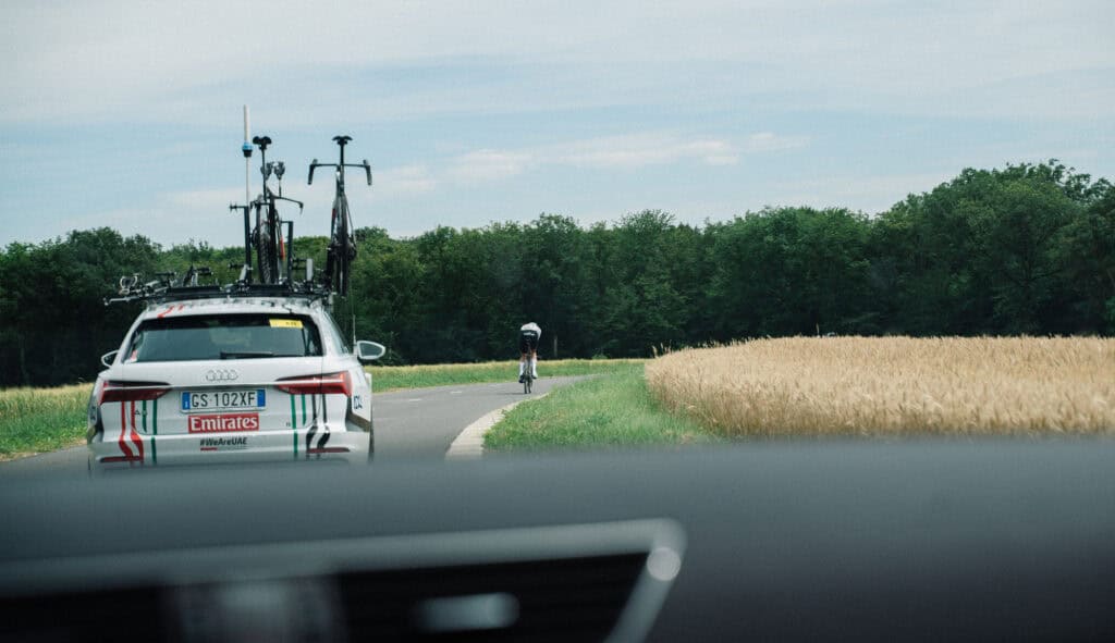 A cyclist and a Tour de France car in the countryside.